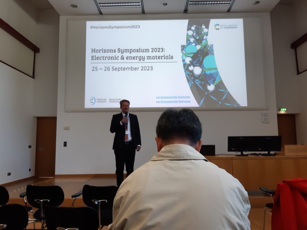 Norbert Koch on stage with a Horizons Symposium welcome slide